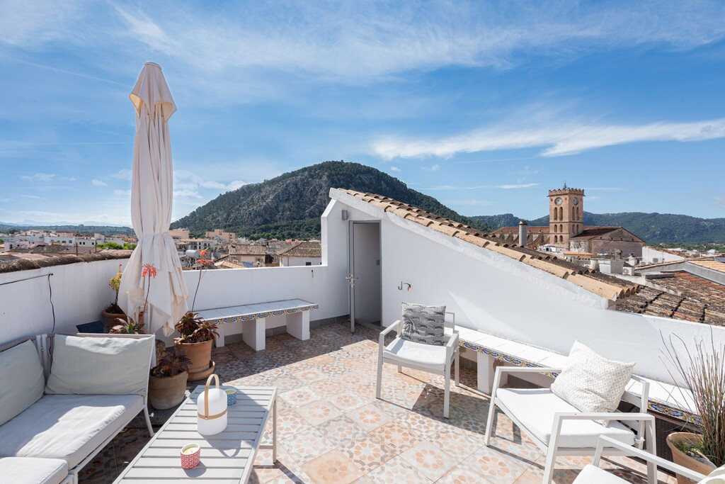 View from a roof terrace over Pollença rooftops and church tower